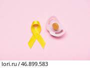 Золотая лента осознания и соска на цветном фоне. Международный день защиты от рака. Стоковое фото, фотограф Pixel_shot / Фотобанк Лори