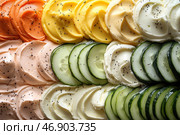 A colorful culinary still life, with slices of fresh cucumber and a variety of creamy spreads neatly arranged. The spreads are arranged in a gradient of colors, from delicate orange and yellow to white and then to rich green. Black seeds (possibly poppy or black pepper) are sprinkled on top, adding textural contrast. The composition looks fresh, appetizing and aesthetically pleasing. Стоковое AI-изображение, AI-художник Анна Кривицкая / Фотобанк Лори