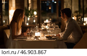Couple enjoying a romantic dinner in an elegant restaurant with soft lighting and a cozy atmosphere at night. Стоковое AI-изображение, AI-художник Сергей Толмачёв / Фотобанк Лори