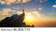 Person standing on mountain top at sunrise looking at sky symbolizing success motivation ambition adventure inspiration achievement, leadership solitude dream altitude. Стоковое фото, фотограф Павел Муравьев / Фотобанк Лори