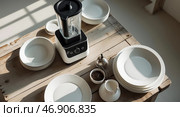 Modern kitchen setup featuring a blender and diningware on a wooden table in a bright, sunlit room. Стоковое AI-изображение, AI-художник Сергей Толмачёв / Фотобанк Лори