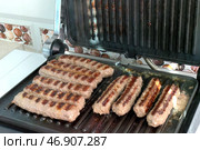 Приготовление чевапчичи (колбасок) на электрическом гриле - Cooking chevapchichi (sausage) on an electric grill. Стоковое фото, фотограф Владислав Дельдюгинов / Фотобанк Лори