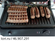 Приготовление чевапчичи (колбасок) на электрическом гриле - Cooking chevapchichi (sausage) on an electric grill. Стоковое фото, фотограф Владислав Дельдюгинов / Фотобанк Лори