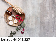 Красивая композиция с деревянным подносом, массажной щеткой для тела, бутылочкой с сывороткой, лепестками роз и свечами на фоне с эффектом состаренности. Стоковое фото, фотограф Pixel_shot / Фотобанк Лори
