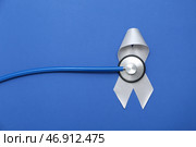 Серая лента осведомлённости со стетоскопом на синем фоне. Концепция рака мозга. Стоковое фото, фотограф Pixel_shot / Фотобанк Лори