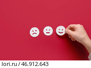 Мужская рука и смайлы для оценки на красном фоне. Концепция опроса. Стоковое фото, фотограф Pixel_shot / Фотобанк Лори