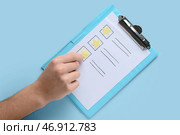 Мужчина принимает участие в опросе на синем фоне, вид сверху. Стоковое фото, фотограф Pixel_shot / Фотобанк Лори