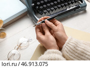 Женские руки с перьевой ручкой, блокнотом, очками и пишущей машинкой на светлом деревянном столе, крупный план. Стоковое фото, фотограф Pixel_shot / Фотобанк Лори