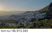 A beautiful landscape and a view of the city with small houses which is located on the mountains with green trees against the blue sky. Стоковое фото, фотограф David Kashakhi / Фотобанк Лори