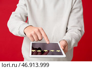 Мужчина с планшетом проходит опрос на красном фоне, крупный план. Стоковое фото, фотограф Pixel_shot / Фотобанк Лори