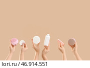 Множество женских рук с бутылочками косметических продуктов, ватным диском и силиконовой щеткой для очищения лица на бежевом фоне. Стоковое фото, фотограф Pixel_shot / Фотобанк Лори