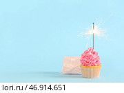 Сладкий праздничный капкейк с бенгальским огнем и подарочной коробкой на синем фоне. Стоковое фото, фотограф Pixel_shot / Фотобанк Лори