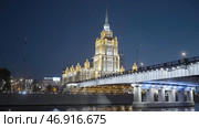 Beautiful huge evening buildings near the river in Moscow were shot from afar on a dark evening with bright lights and lanterns that glow . Стоковое фото, фотограф David Kashakhi / Фотобанк Лори