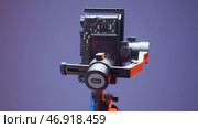 A rotating tripod for shooting with an attached camera on a purple background. Редакционное фото, фотограф David Kashakhi / Фотобанк Лори