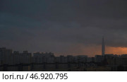 High rise building surrounded by residential houses, business center on heavy sunset sky background, time lapse effect. Стоковое фото, фотограф David Kashakhi / Фотобанк Лори