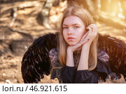 Enigmatic Teen Girl Model With Dark Wings in a Serene Outdoor Setting During Golden Hour. Стоковое фото, фотограф Aleksandr Golubev / Фотобанк Лори