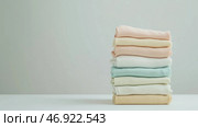 Stacked towels in soft colors arranged neatly on a plain surface in a bright indoor setting. Стоковое AI-изображение, AI-художник Сергей Толмачёв / Фотобанк Лори
