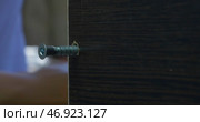Man using an electric hand drill to drive a screw into a board. Стоковое фото, фотограф David Kashakhi / Фотобанк Лори