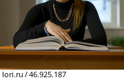 Woman sitting at the table leafing through the book. Стоковое фото, фотограф David Kashakhi / Фотобанк Лори