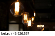 Decorative antique edison style light tungsten bulbs against brick wall background. Стоковое фото, фотограф David Kashakhi / Фотобанк Лори