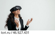 Smiling woman enjoys virtual reality experience in a modern setting. Женщина в официальном наряде улыбается во время работы с технологией виртуальной реальности. Она выглядит взволнованной и погруженной в свои переживания, наслаждаясь инновационной деятельностью в минималистичном помещении. Стоковое AI-изображение, AI-художник Katsiaryna Repich / Фотобанк Лори