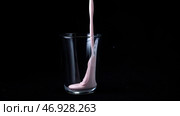 In transparent glass pour viscous pink milkshake on black background. Стоковое фото, фотограф David Kashakhi / Фотобанк Лори