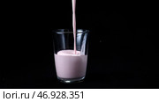 In transparent glass pour viscous pink milkshake on black background. Стоковое фото, фотограф David Kashakhi / Фотобанк Лори