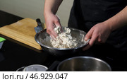 Man kneading dough with his hands in a metal bowl at the kitchen. Стоковое фото, фотограф David Kashakhi / Фотобанк Лори