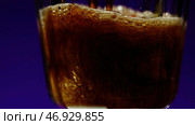 Coke soda in transparent glass on a colorful lighted wall background. Стоковое фото, фотограф David Kashakhi / Фотобанк Лори