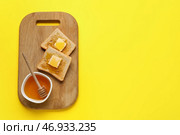 Деревянная доска с вкусными поджаренными хлебцами с медом и маслом на желтом фоне. Стоковое фото, фотограф Pixel_shot / Фотобанк Лори