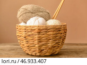 Плетеная корзина с вязальной пряжей и спицами на деревянном столе на цветном фоне. Стоковое фото, фотограф Pixel_shot / Фотобанк Лори