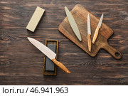 Доска с набором ножей и точильным камнем на деревянном фоне. Стоковое фото, фотограф Pixel_shot / Фотобанк Лори