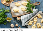 Противень и доска с сырыми чесночными булочками на цветном фоне. Стоковое фото, фотограф Pixel_shot / Фотобанк Лори