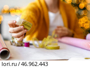 Красивая молодая женщина упаковывает рождественский подарок дома, крупным планом. Стоковое фото, фотограф Pixel_shot / Фотобанк Лори