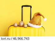 Чемодан, шляпа Санты и украшения на цветном фоне, крупным планом. Концепция рождественских каникул. Стоковое фото, фотограф Pixel_shot / Фотобанк Лори