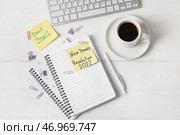 Чашка кофе, компьютерная клавиатура, канцелярские принадлежности, стикеры с текстом НОВОГОДНЯЯ РЕЗОЛЮЦИЯ 2022 и НЕ ЗАБЫВАЙТЕ на белом деревянном фоне. Стоковое фото, фотограф Pixel_shot / Фотобанк Лори