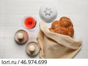 Традиционный хлеб халы с бокалом вина, свечами и еврейской кепкой на белом деревянном фоне. Шаббат Шалом. Стоковое фото, фотограф Pixel_shot / Фотобанк Лори