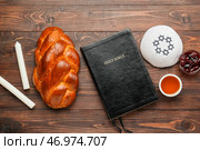 Традиционный хлеб халы с Танахом, свечами и еврейской кепкой на деревянном фоне. Шаббат Шалом. Стоковое фото, фотограф Pixel_shot / Фотобанк Лори