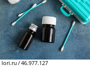 Флаконы с йодом, ватные тампоны и контейнер с таблетками на синем фоне. Стоковое фото, фотограф Pixel_shot / Фотобанк Лори