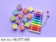 Деревянные кубики с буквами и ксилофон на фиолетовом фоне. Стоковое фото, фотограф Pixel_shot / Фотобанк Лори