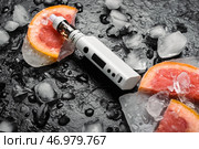Современный вейп-мод, грейпфрут и кубики льда на черном фоне, крупным планом. Стоковое фото, фотограф Pixel_shot / Фотобанк Лори