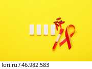 Лента осведомленности с образцом крови, таблетками и блоками на желтом фоне. Концепция гепатита. Стоковое фото, фотограф Pixel_shot / Фотобанк Лори