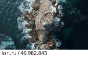 Blue waves beat against stone ledge with lighthouse on sunny day. Стоковое фото, фотограф David Kashakhi / Фотобанк Лори
