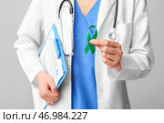 Женщина-врач с зеленой лентой и буфером обмена на сером фоне. Концепция рака печени. Стоковое фото, фотограф Pixel_shot / Фотобанк Лори