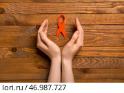 Женщина с оранжевой лентой осведомленности на деревянном фоне. Концепция рака почки. Стоковое фото, фотограф Pixel_shot / Фотобанк Лори