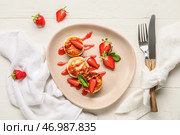 Тарелка с вкусными сырниками, покрытыми соусом и ягодами на белом деревянном фоне. Стоковое фото, фотограф Pixel_shot / Фотобанк Лори