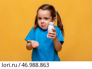 Puzzled and clueless little girl with arms out, shrugging her shoulders, holding bottle with yogurt, saying: who cares, so what, I don't know. Human emotions, facial expressions, yellow background. Стоковое фото, фотограф Ирина Михайличенко / Фотобанк Лори