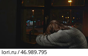 Young woman sits on window and looks sadly at night city. Стоковое фото, фотограф David Kashakhi / Фотобанк Лори
