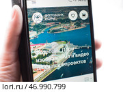 Смартфон с открытым сайтом фотобанка Лори в руке. Редакционное фото, фотограф Алиса Сокол / Фотобанк Лори