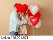 Прекрасная пара, закрывающая лицо сердцем на бежевом фоне. Празднование Дня Святого Валентина. Стоковое фото, фотограф Pixel_shot / Фотобанк Лори